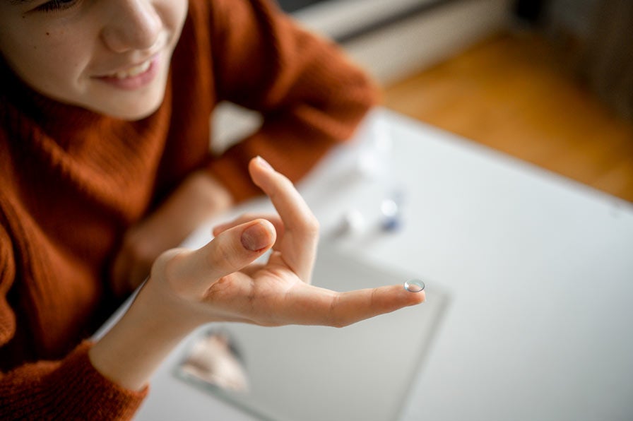 Woman's hands with contact lens on her finger