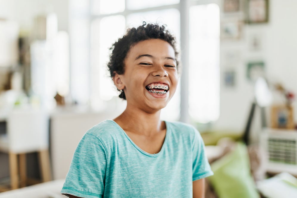 Preteen in blue shirt smiling with braces