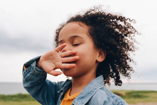 Portrait of curly haired young curl covering her mouth outside