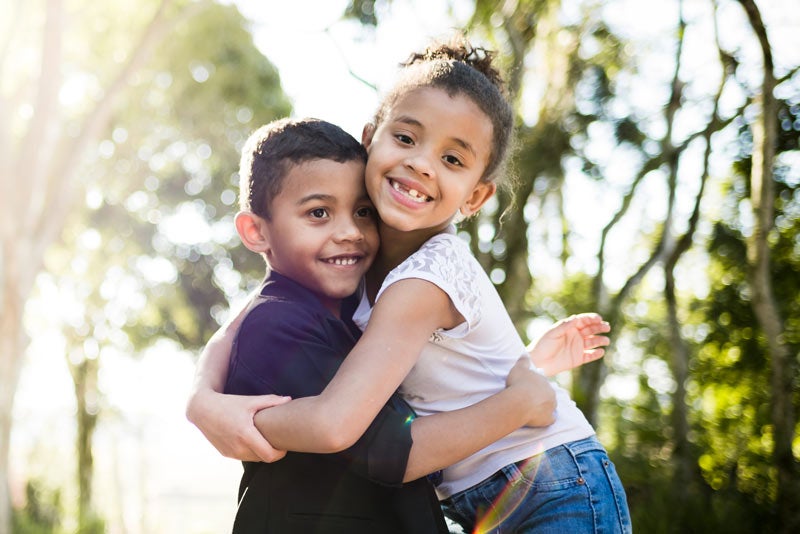 Brother and sister hugging outdoors