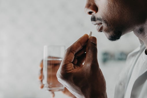 Man taking medicine with glass of water