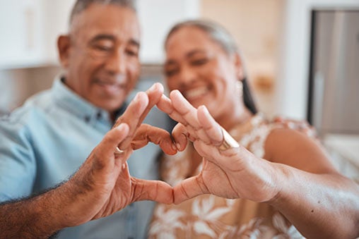 Senior couple holding hands together in a heart