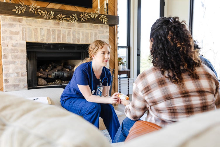 Female home health nurse discusses medication with patient's daughter
