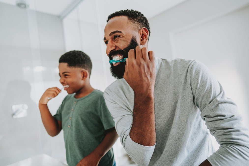 Father and son brushing teeth in front of mirror