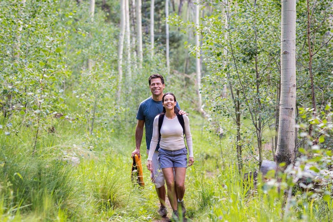 Middle aged couple hiking in the woods together surrounded by foliage