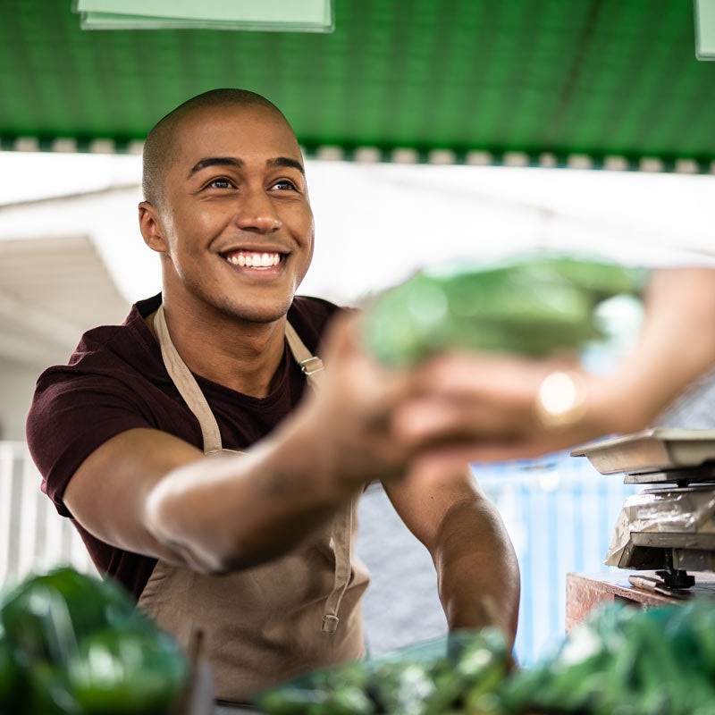 Man giving customer vegetables at outdoor market