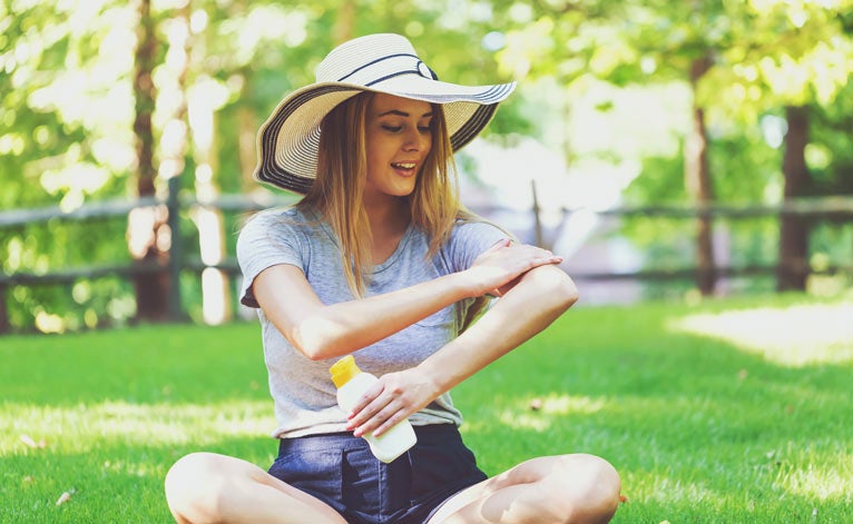 Young woman applying sunscreen