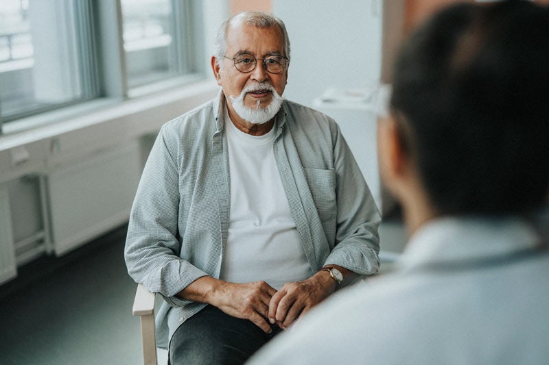 Older man talking with doctor in exam room
