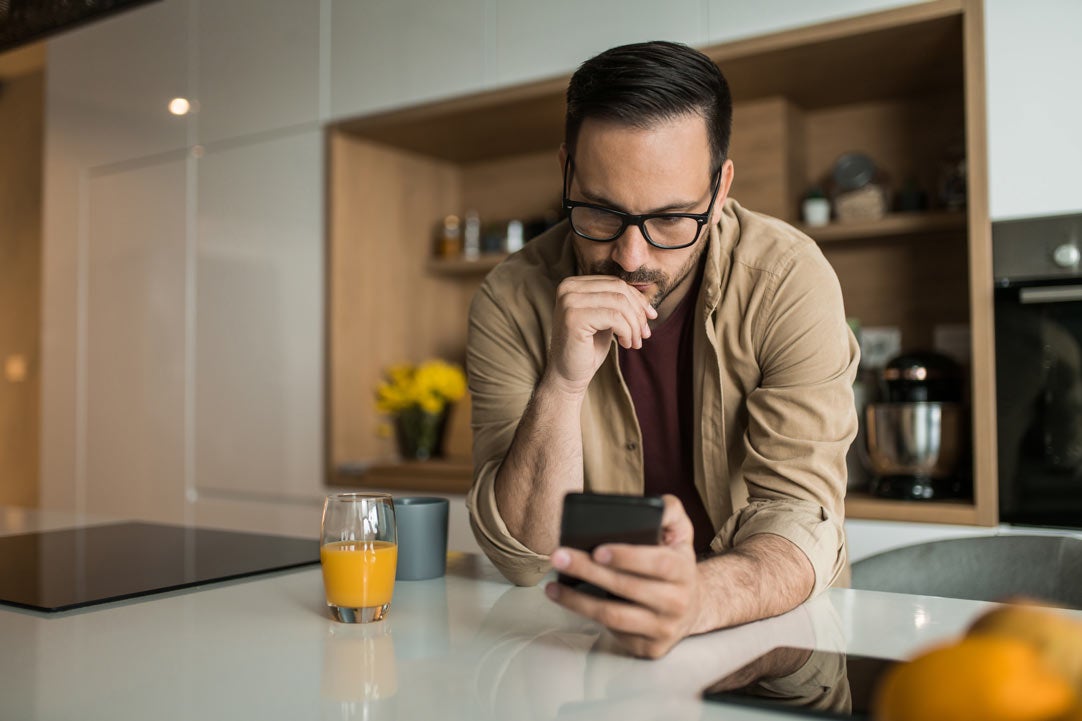 Man scrolling on phone in kitchen
